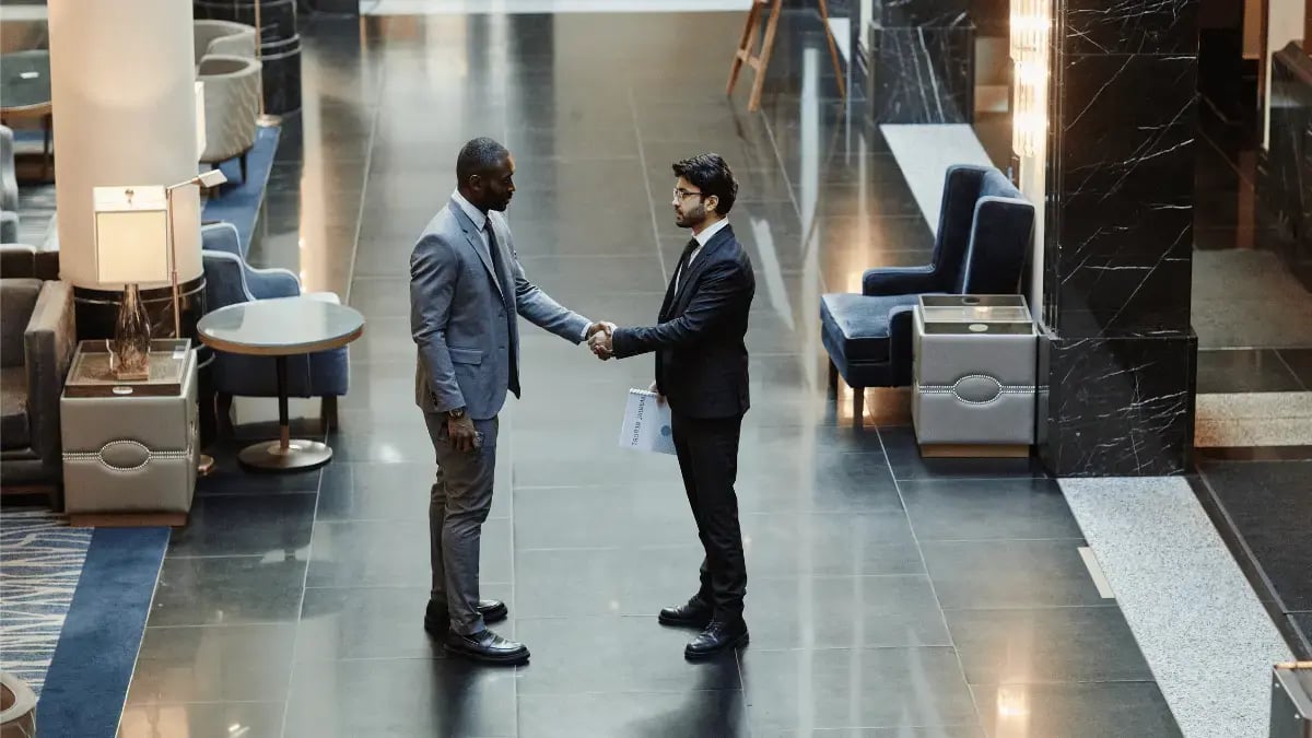 Two businessmen shaking hands in a modern business setting, symbolizing the challenges and solutions in international B2B debt collection.